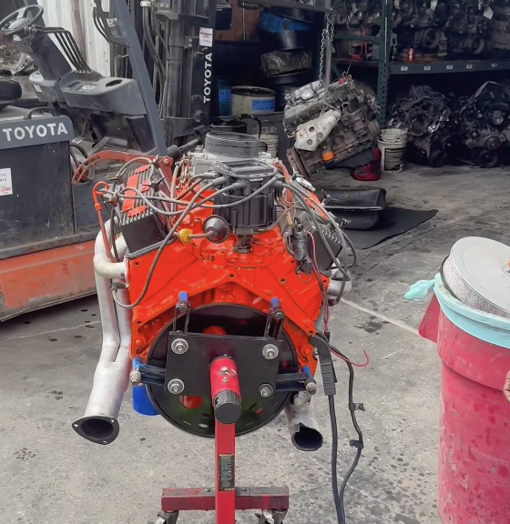 Motor V8 reconstruido sobre un soporte en Villanueva Auto, con un montacargas y piezas usadas al fondo