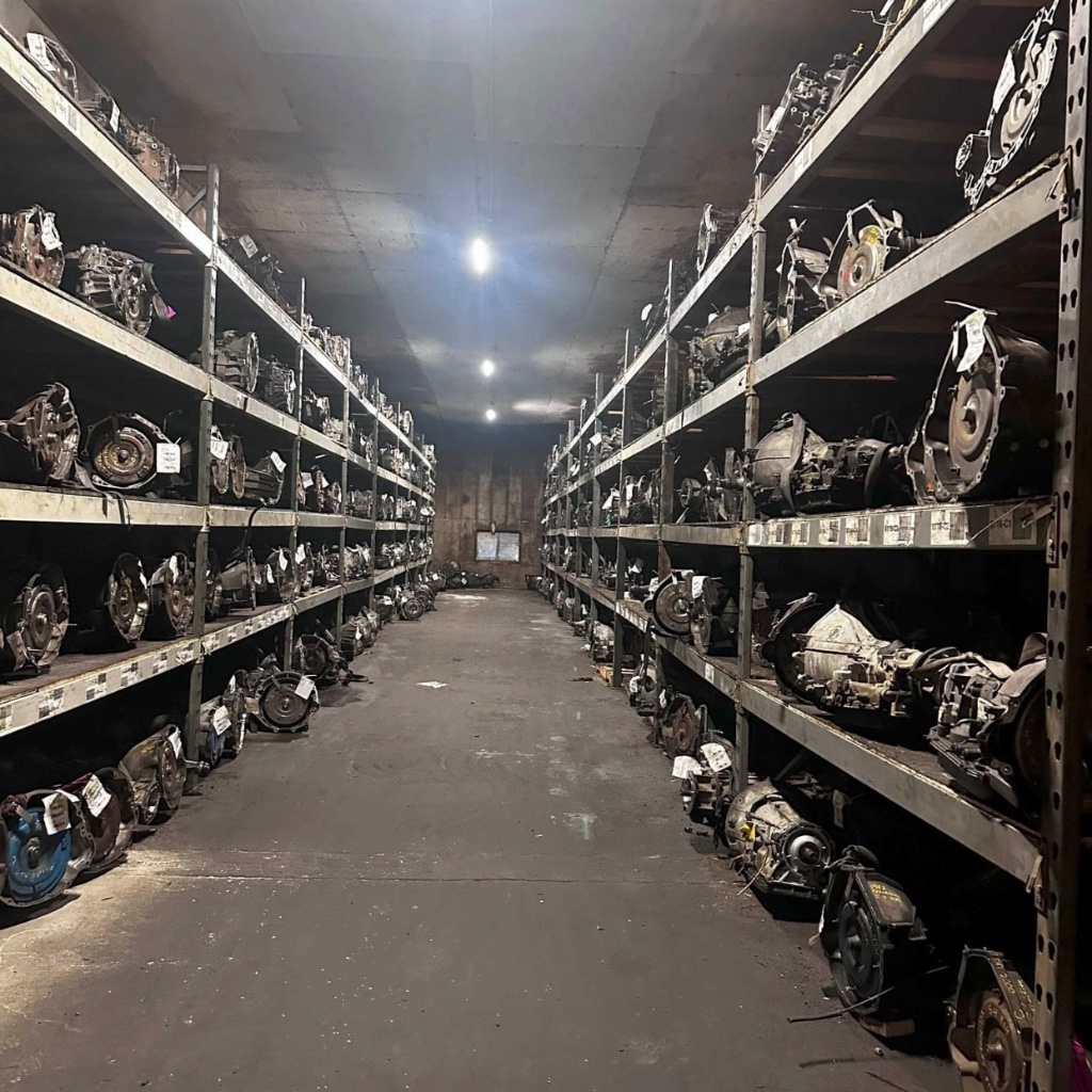 Pasillo de transmisiones usadas en estanterías de acero en la bodega de Villanueva Auto en Salinas
